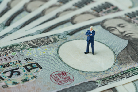 miniature figure businessman president or prime minister thinking standing on pile of japanese yen banknotes as financial economic leader concept.の写真素材