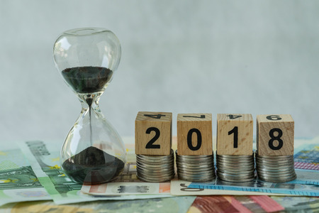 Year 2018 business time countdown or long term investment concept as hourglass or sandglass on pile...