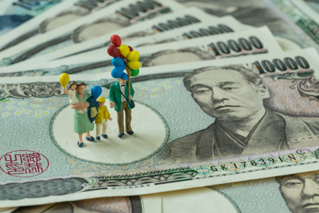 miniature figure happy family holding balloons standing on pile of japanese yen banknotes as happy financial retirement senior people.の写真素材