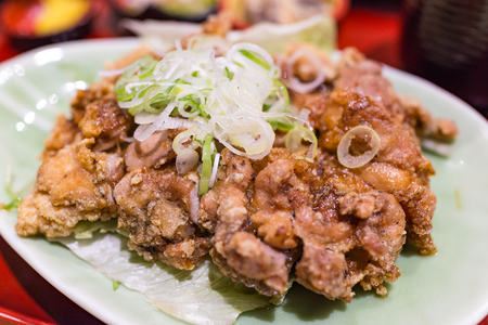 Traditional delicious japanese fried chicken with sauce and vegetable on top in green dish restaurant.の写真素材