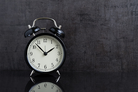 Time passing with black alarm clock in retro dark black background with copy space.