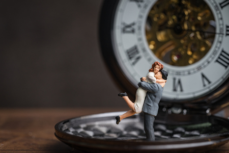 Miniature happiness couple standing on vintage pocket watch, husband holding his wife celebrate valentines'day or forever love concept.の写真素材