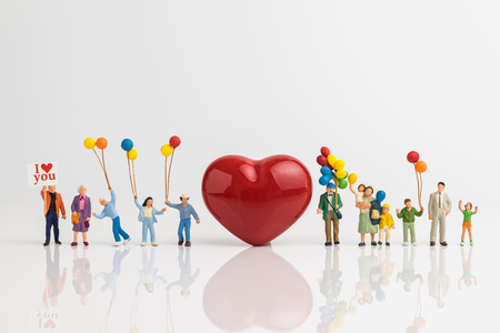 Miniature people happy love family holding balloons with red heart shape on white background using as happy valentine's day concept.の写真素材