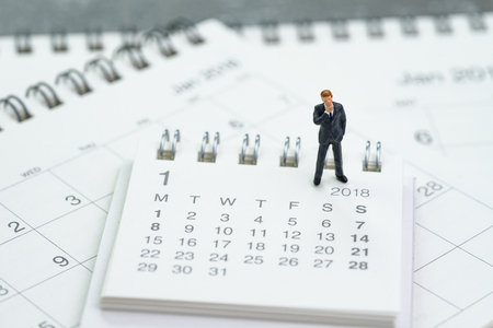 Miniature businessman thinking and standing on calendars using as business goals or future thinking.の写真素材