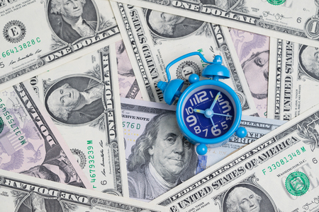 Blue retro alarm clock on US dollar banknotes as money time concept.の写真素材