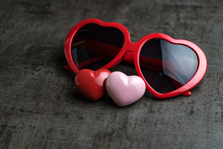 Red and pink heart shapes with heart shape eyeglasses on black cement floor as Valentine's day concept.の写真素材