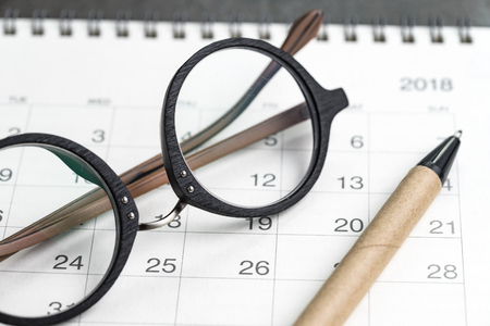 Closed up of eyeglasses and pen on calendar using as date orgainizer or year planning concept.の写真素材