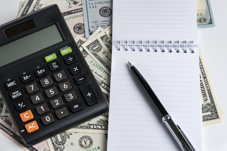 White paper note pad and pen, calculator on dollar banknotes using as business accounting or tax calculation concept.の写真素材