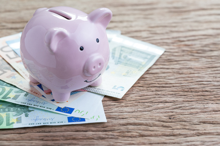Money savings financial account, Europe economics concept, pink piggy bank on pile of Euro banknotes on wooden table, future growth of compound interest in saving or investing idea.の写真素材