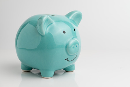 Blue piggy bank on reflection floor and seamless white background.の写真素材
