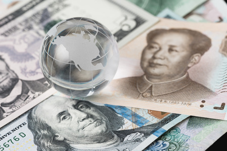 US and China trade barrier, an action by a government that makes trade between the country and other countries more difficult, decoraton glass globe on US dollar and china yuan banknotes.の写真素材