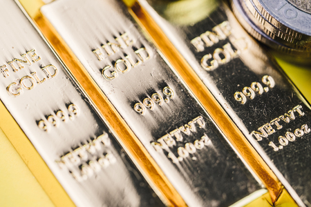 Pure 999.9 shiny fine gold bullions ingot bars with money coins, closed up macro shot as financial asset, investment and wealth concept.の写真素材