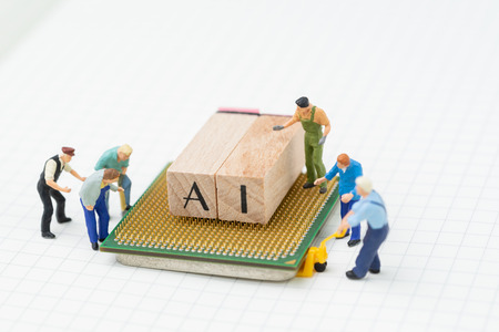 AI or Artificial Intelligence concept, miniature people figure, workers, engineers building or moving wooden stamp block to arrange the word AI on computer chip on grid line idea notebook.の写真素材