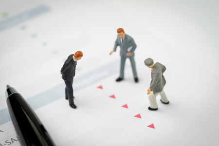 Financial crisis, decline or investment price drop concept, miniature professional businessmen standing and looking, review on red down arrows stock market data with shock and panic customer.の写真素材