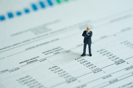 Investment, financial report analysis concept, miniature people figurine success businessman standing on printed stock exchange data document.の写真素材