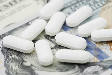 Health care, pharmacy and medical industry business concept, 500 miligrams white tablet pills on face of US dollar banknotes, money and expense for illness.の写真素材