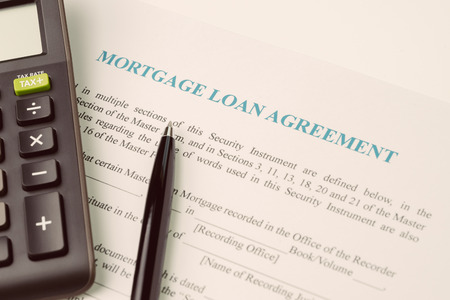 Mortgage loan agreement sign contract concept, pen with calculator on mortgage form or contract, long term debt, home and house owner or real estate investment.の写真素材