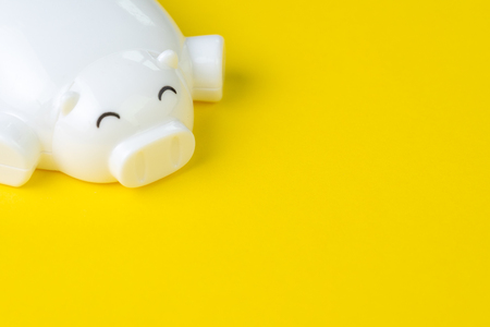 Financial, savings, budget, cost or investment background concept with copy space, white happy smiling piggy bank on vivid yellow background, use as easy method to earn money and rich.の写真素材