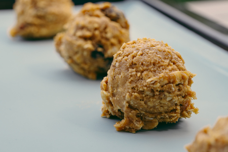 Closed up of cookie dough on baking sheet, brown hazelnuts, raisin and oatmeal put in scoop before put in the oven.の写真素材
