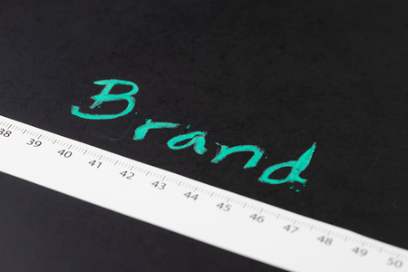 Brand engagement KPI with measurable metrics in online and offline marketing campaign concept, measuring tape with centimeter with handwriting chalk word Brand on blackboard.の写真素材