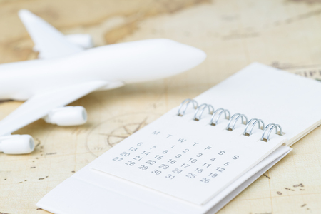 Transportation, travel, holiday or vacation schedule or planning concept, small calendar with toy airplane on  vintage world map with compass, next destination, new adventure journey.の写真素材