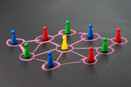 Social network, connect or relation concept, game plastic figure on colorful pastel chalk line link and connect between multiple circles or tiers on dark blackboard.の写真素材
