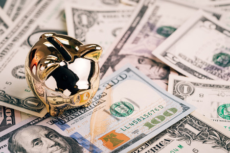 Success growth investment, financial background or saving deposit for the year of pig concept, shiny golden piggy bank or coin bank on pile of US dollar banknotes money.の写真素材