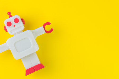 Chatbot or AI Artificial Intelligence or robotic concept, cute vintage look plastic robot on vivid yellow background.の写真素材