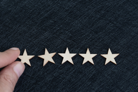 Hand putting 5 stars on dark texture black background with copy space using as customer experience, review or rating, the satisfaction score and comment that user feedback for product and service.の写真素材
