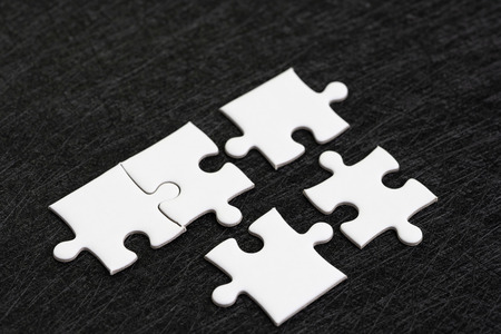 Closed up of white jigsaw puzzle on dark black background using as answer, solution, completion or...