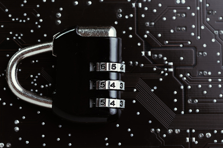 Digital cyber safety or security encryption concept, code numbers on combination pad lock on computer circuit board with solder, technology to encode online information or data protection.の写真素材