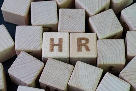 HR, Human Resources and recruitment concept by cube wooden block with alphabet building the word HR at the center on dark blackboard background.の写真素材
