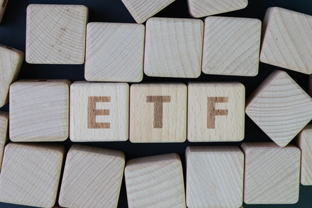 ETF, Exchange Traded Fund concept, cube wooden block with alphabet building the word ETF at the center on dark blackboard background.の写真素材
