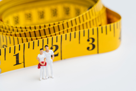 Fitness, exercise or weight control concept, miniature healthy people figure in white, man and woman...