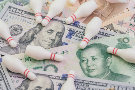 US and China Trade war and tariff negotiation fail concept, bowling pin falling apart on United States America and Chinese banknotes, crisis situation metaphor.の写真素材