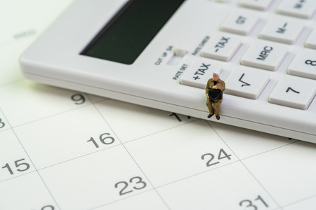 Tax calculation, budget or saving and investment schedule, miniature figure businessman sitting on...