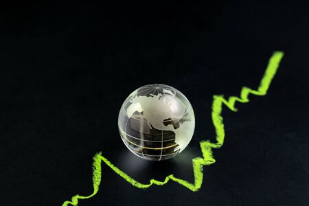 USA or America stock and investment growth, decorate shiny glass globe with United State map on dark black blackboard with chalk drawing green line as stock return growth graph with copy space.の写真素材