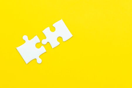 2 jigsaw puzzle on solid yellow background using as 2 important thing combine or working together to success or solve problem.の写真素材