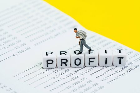Business, investment or company profit concept, miniature businessman walking on cube block with alphabet building word Profit on  bank account with plus sign and numbers.の写真素材