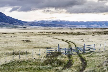 Amazing view of rural road into the farm with fence and white yellow grass with background of nature...