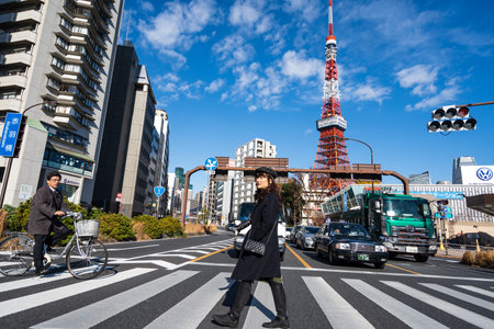 Tokyo, Japan - December 25, 2018: People walking across the street in front of Tokyo Tower in beautiful cloudy blue sky.のeditorial素材