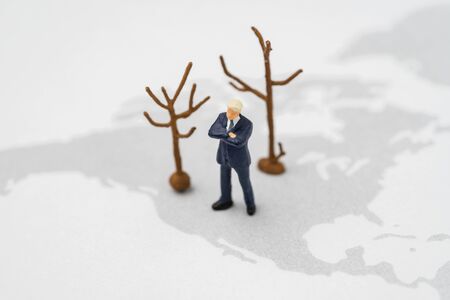 Miniature US America president leader standing on USA map with dried trees represent climate change...