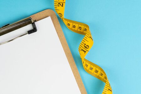 Healthy eating plan, diet or fitness planning, blank white paper on clipboard with measuring tape on...