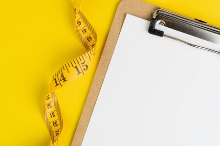 Healthy eating plan, diet or fitness planning, blank white paper on clipboard with measuring tape on...