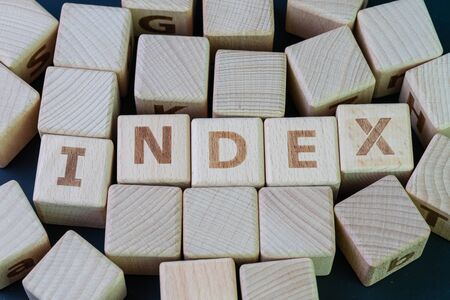 Index fund, passive investing with low cost concept, cube wooden block with alphabet combine the word Index on black chalkboard background.の写真素材