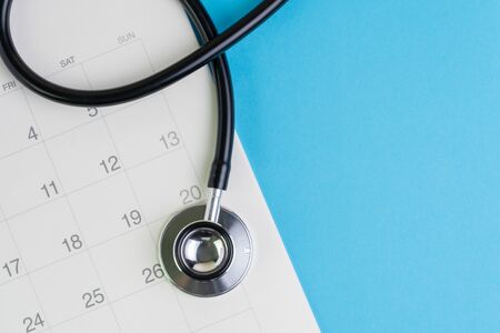 Health care and medical exam schedule calendar, reminder or appointment concept, doctor's stethoscope on white clean calendar with date on blue background with copy space.の写真素材