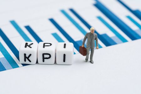 KPI, Key Performance Indicator for company goal concept, small cube block with alphabets building the word KPI with miniature businessman in suit holding briefcase on yearly chart and graph reports.の写真素材