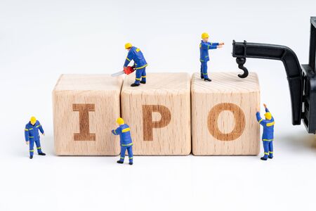 Cube wooden block with alphabets combine the word IPO with miniature people men help building with crane on white background using as Initial Public Offerings, company going public in stock market.の写真素材