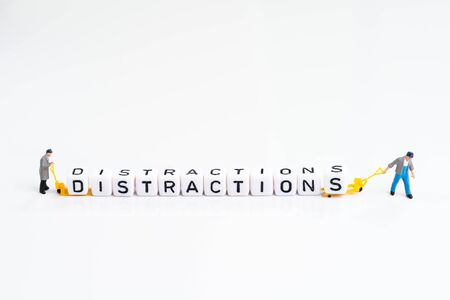 Miniature people man pulling forklift with cube small block building the word Distractions on solid white background using as noise or things that draw attention to losing focus.の写真素材