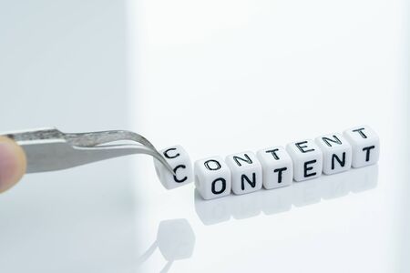 Content is king in advertising and marketing concept, hand holding tweezer with cube block alphabet...